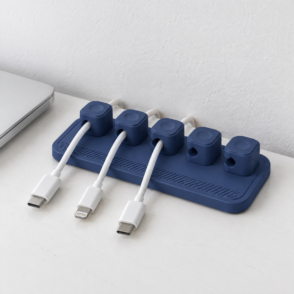 Blue magnetic cable holder at the back of a white desk, holding white charging cables