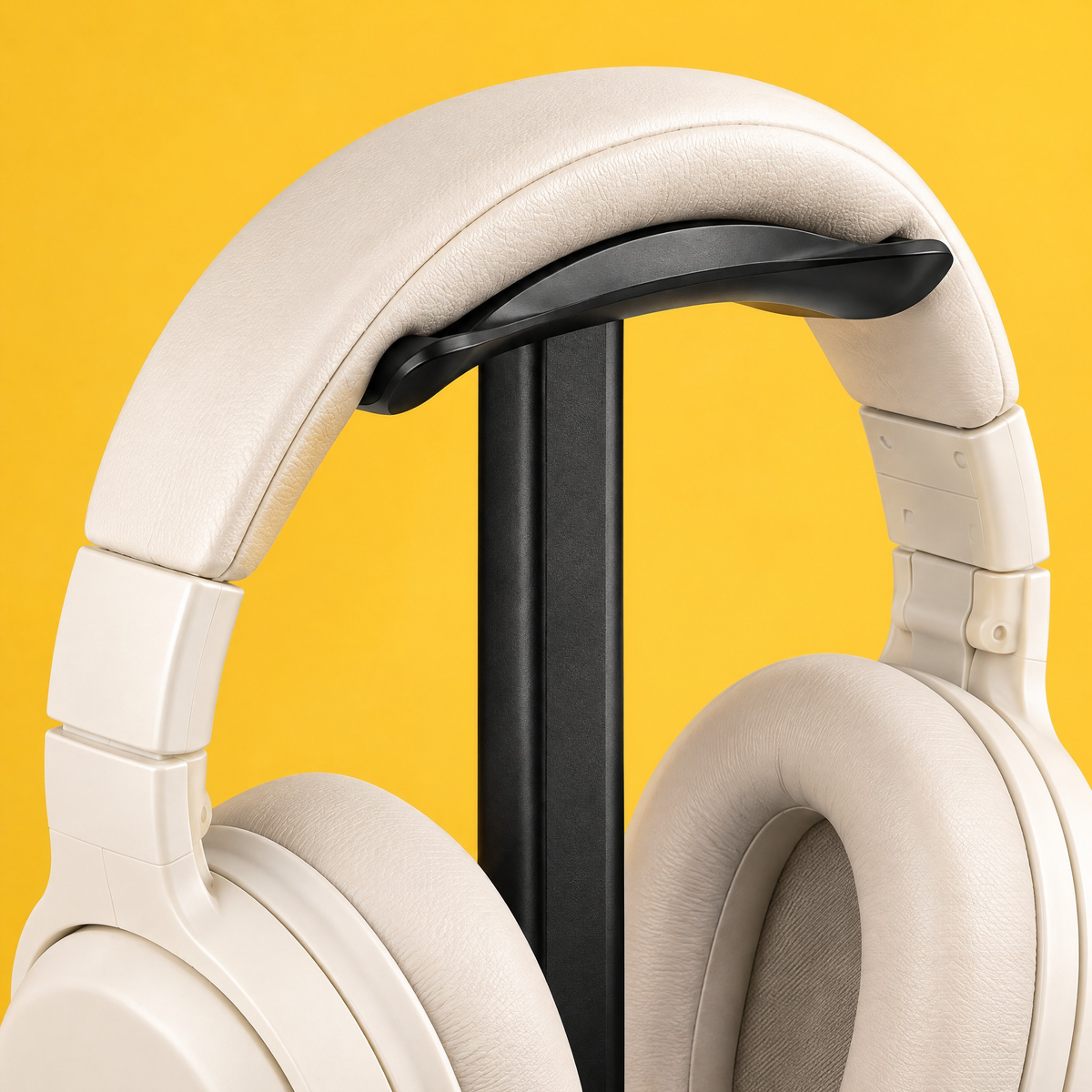 Close-up of the curved headrest of the black headphone stand holding cream headphones