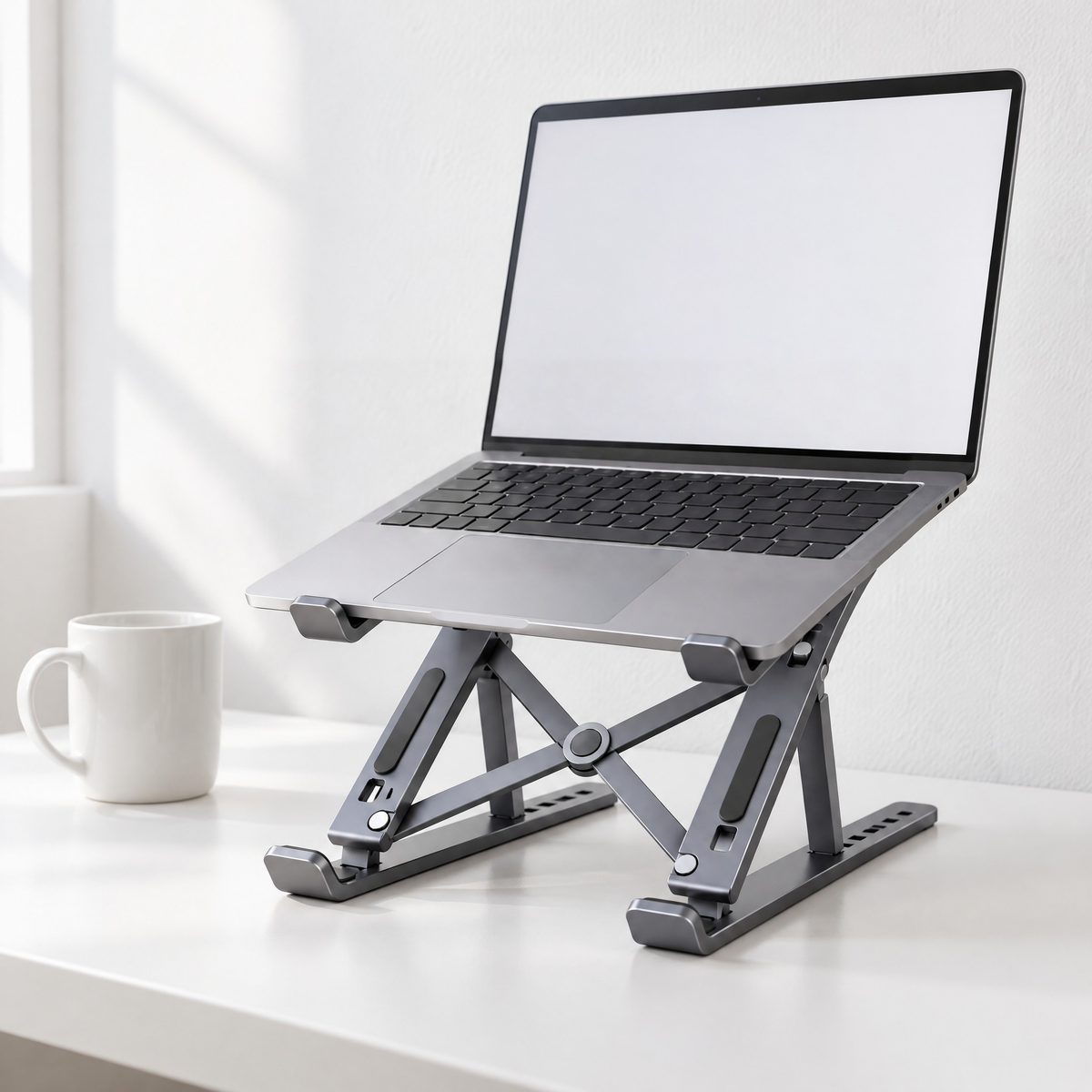 Standard folding aluminium laptop stand in grey holding a laptop on a white desk