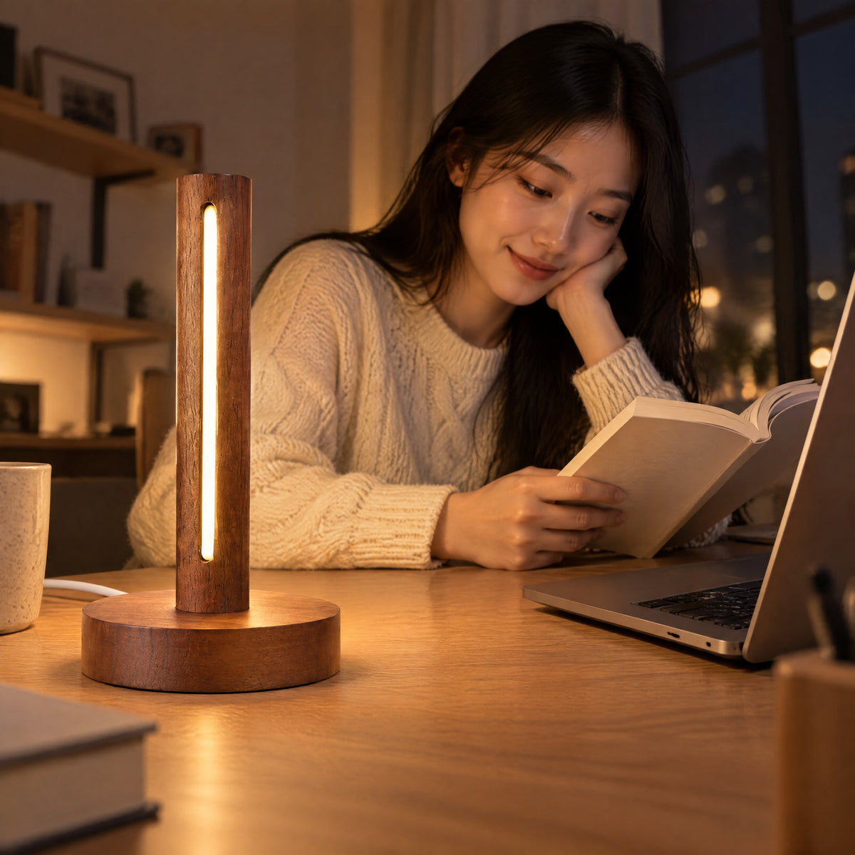 Woman reading at her desk in the evening, the Ember walnut lamp glowing beside her