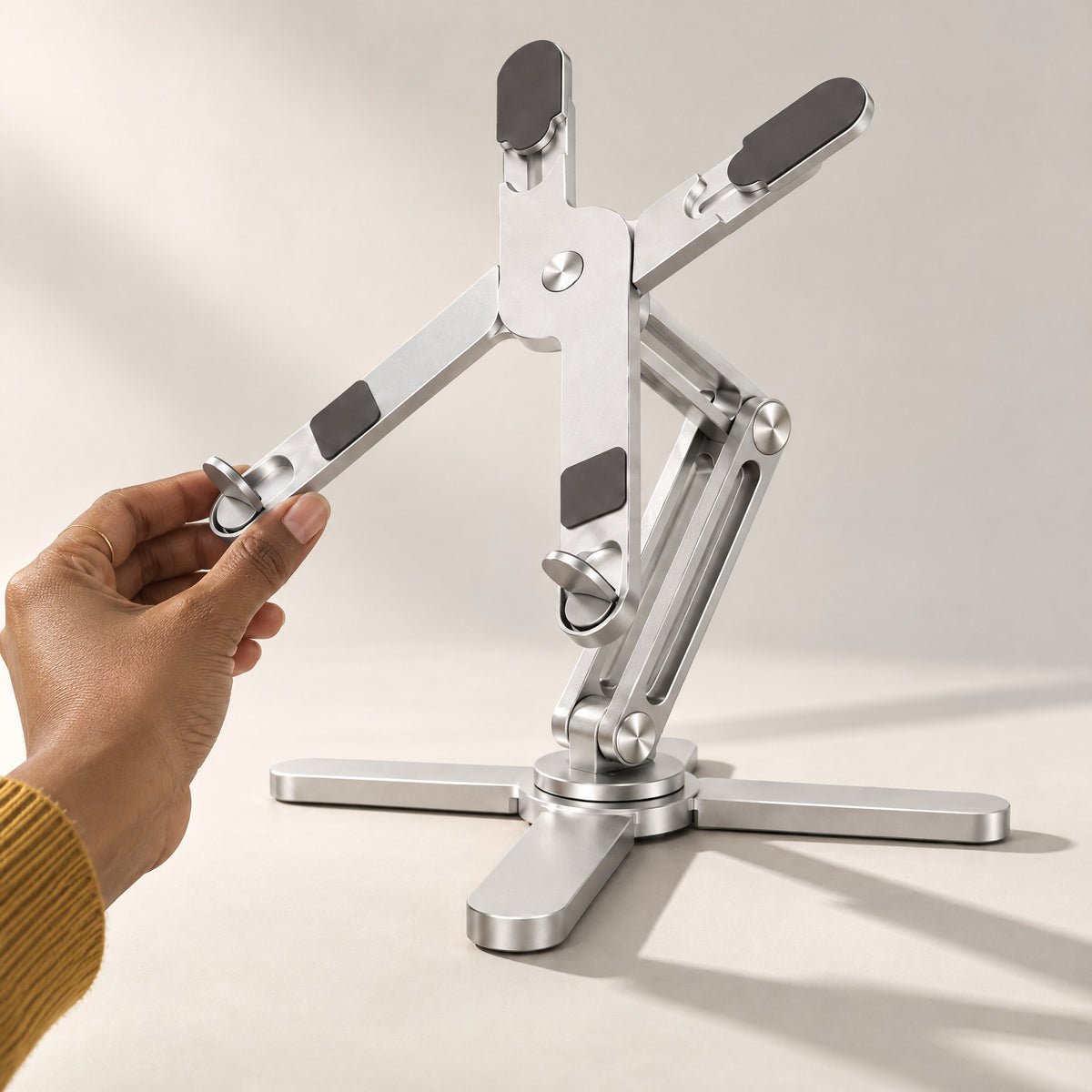 Hand adjusting the angle of the X-shaped platform on the AeroSpin 360 laptop stand