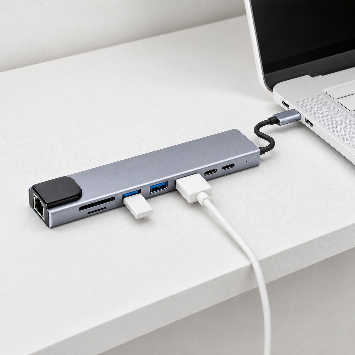 Junction 8-in-1 USB-C hub plugged into a white laptop, with an HDMI cable and a flash drive in its ports
