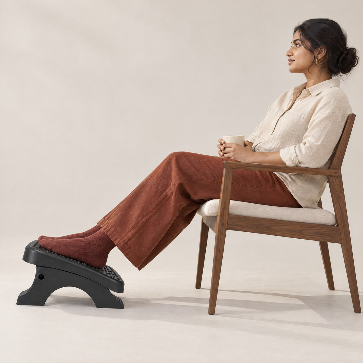 Woman leaning back in a chair with her feet on the Ease footrest, side view