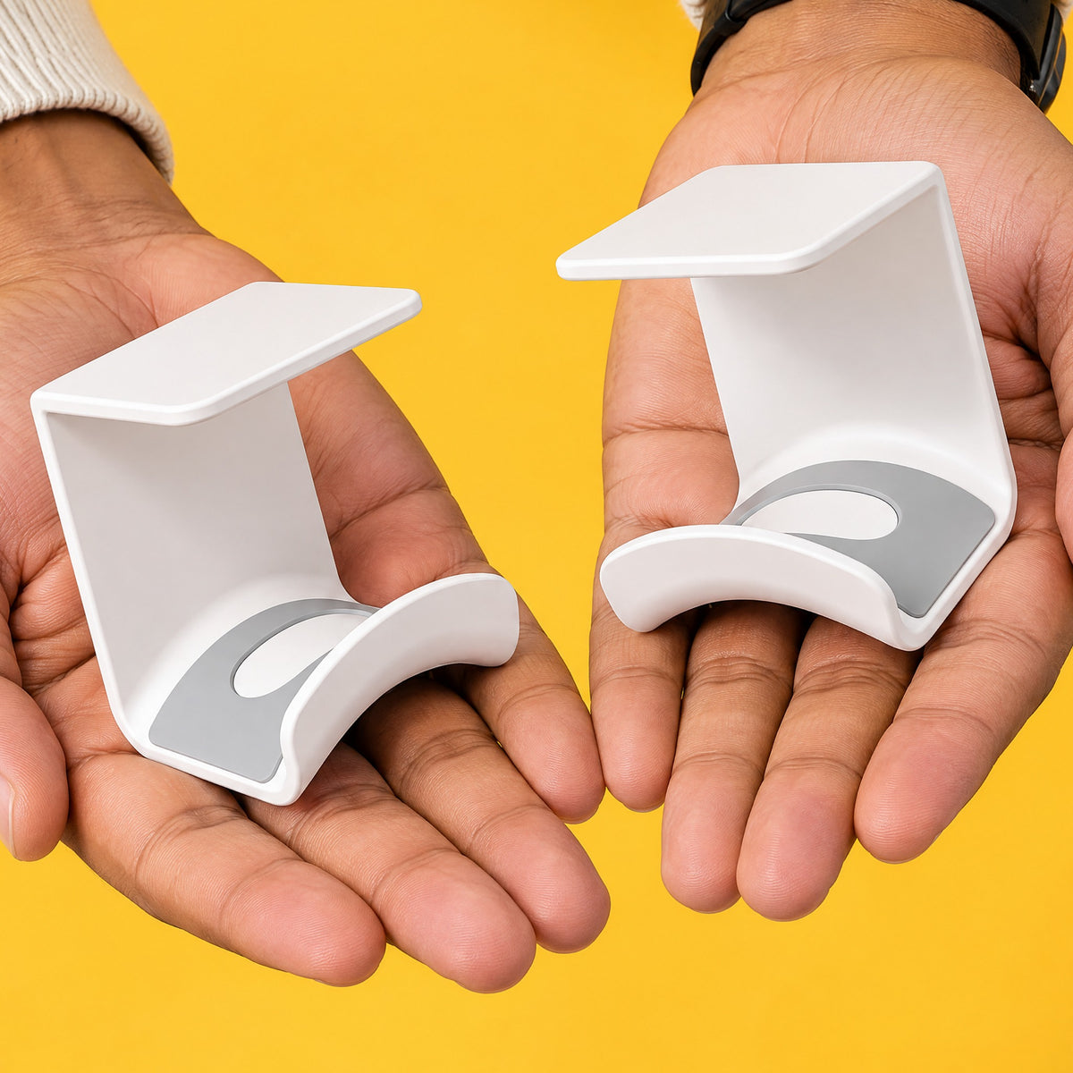 Two white Eave under-desk headphone hooks, one on each open palm