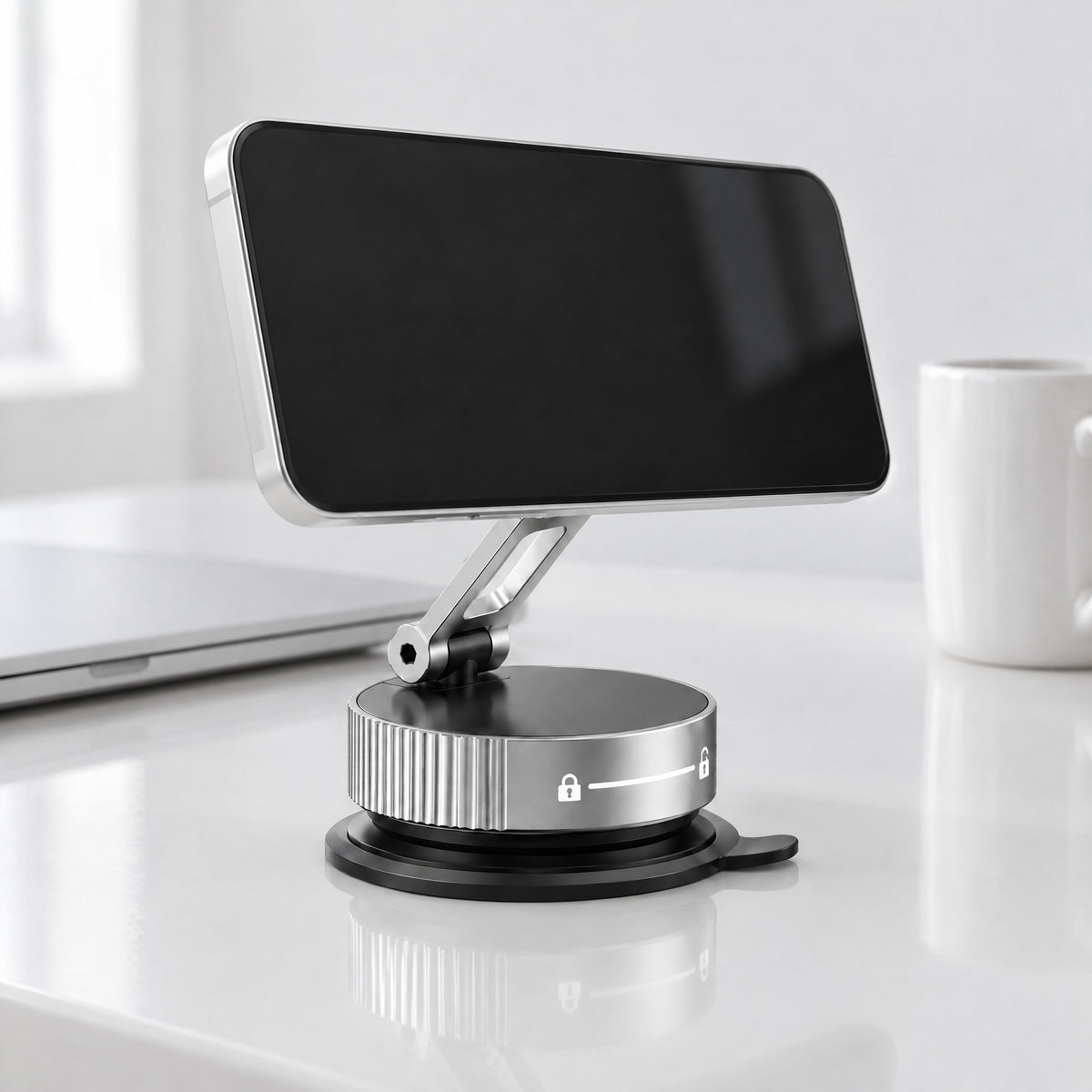 Limpet folding suction phone mount in silver on a glossy white desk, holding a phone sideways