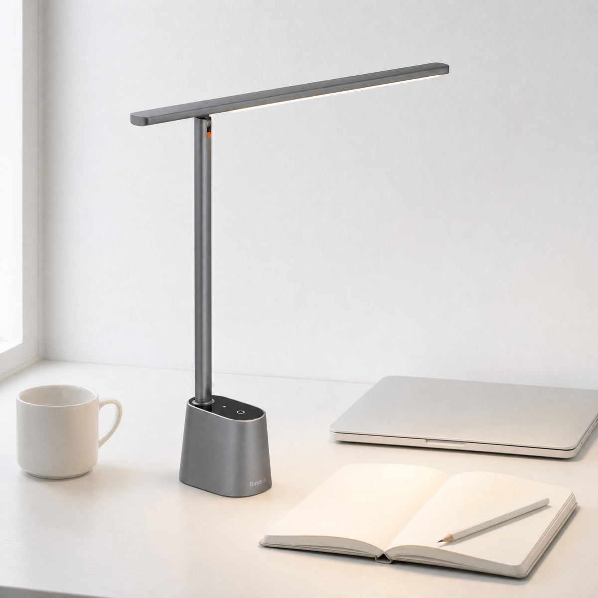 Grey Lintel folding LED desk lamp switched on over an open notebook on a white desk