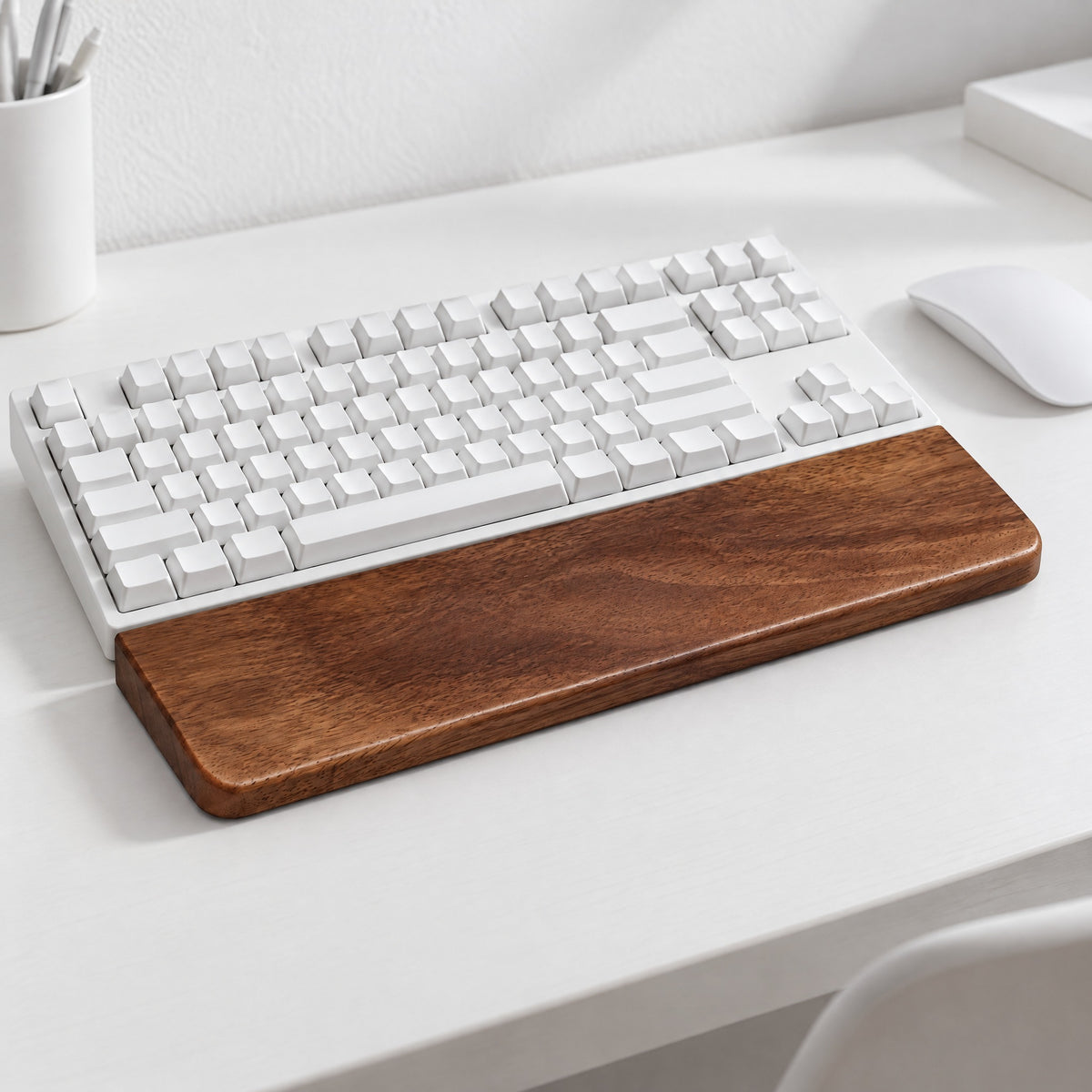 Sill walnut wrist rest in front of a white keyboard on a white desk