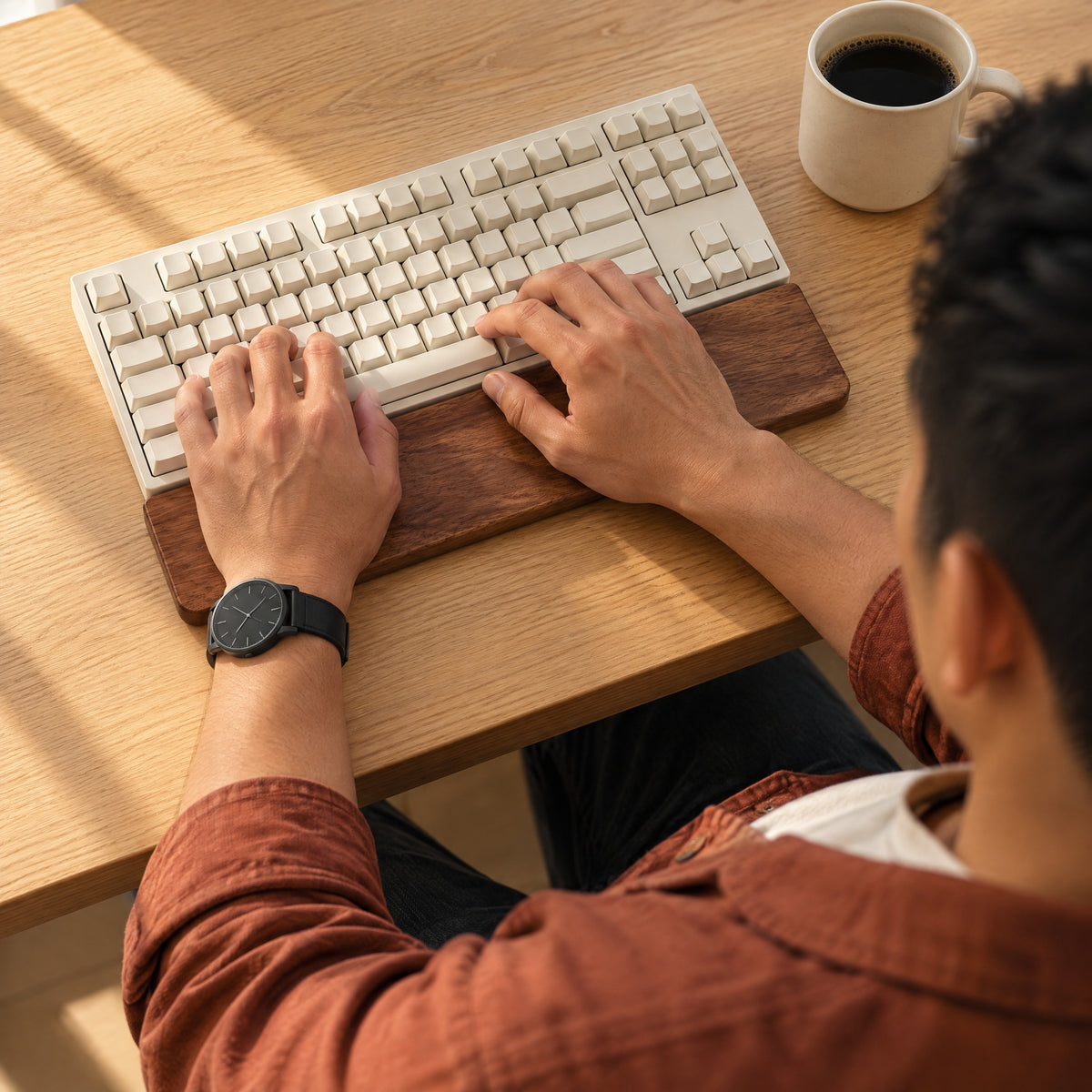 Man typing with the heels of both hands resting on the Sill walnut wrist rest