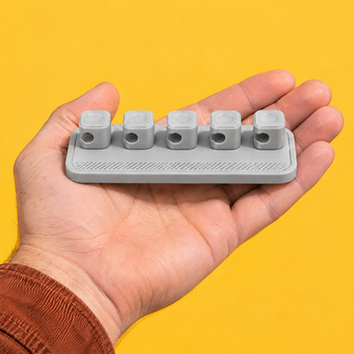 Grey magnetic cable holder with its five clips resting on an open palm, showing its size