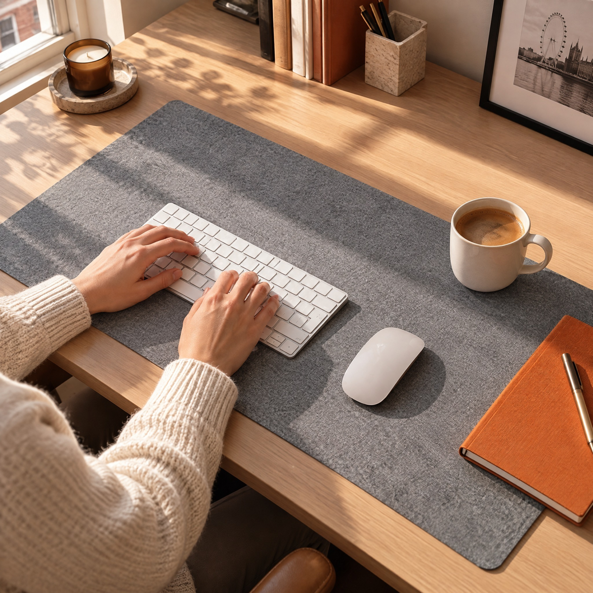 Home-office desk with a grey felt desk mat, keyboard, mug and orange notebook