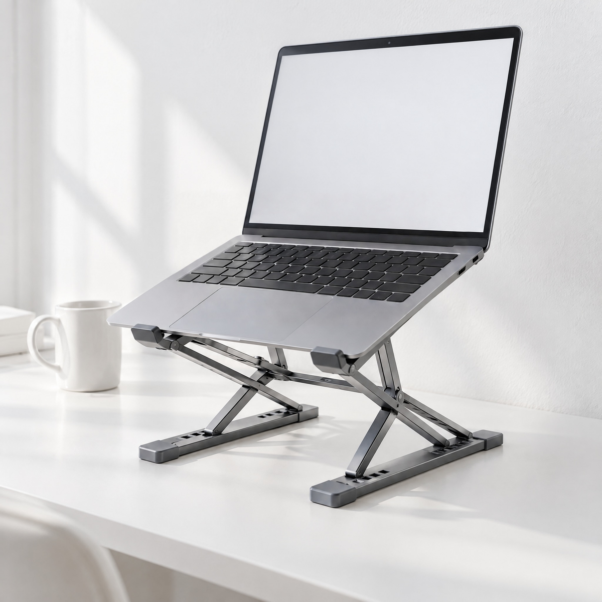 Tall folding aluminium laptop stand in grey holding a laptop on a white desk