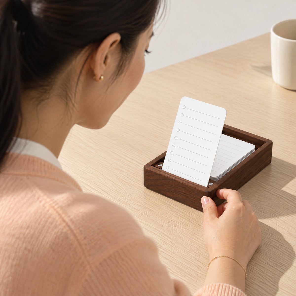 Woman adjusting the Ledger walnut list holder with a fresh to-do card in its slot