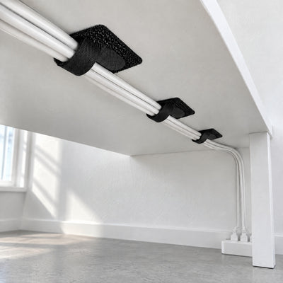 Three black Velor cable ties holding a bundle of white cables under a white desk