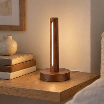 Ember walnut lamp lit on a bedroom shelf beside books