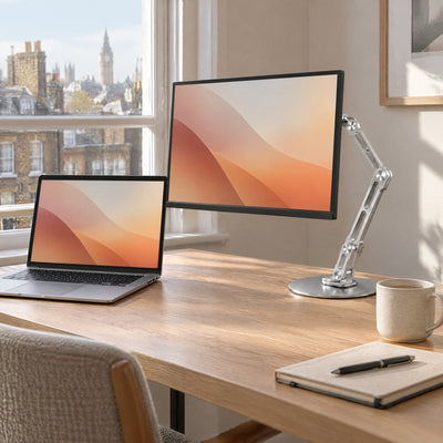Reach stand holding a portable monitor beside a laptop on an oak desk