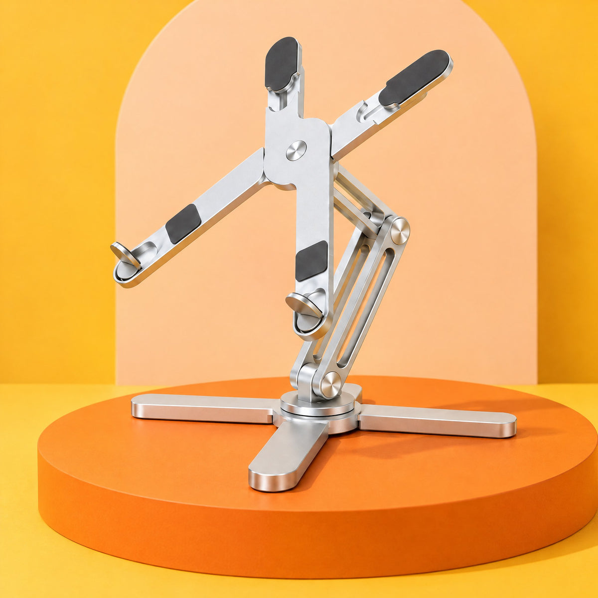 Silver AeroSpin 360 laptop stand on an orange podium against a yellow and peach backdrop