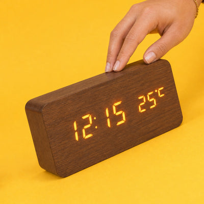 Fingertips tapping the top of the brown Grain clock to wake its amber display