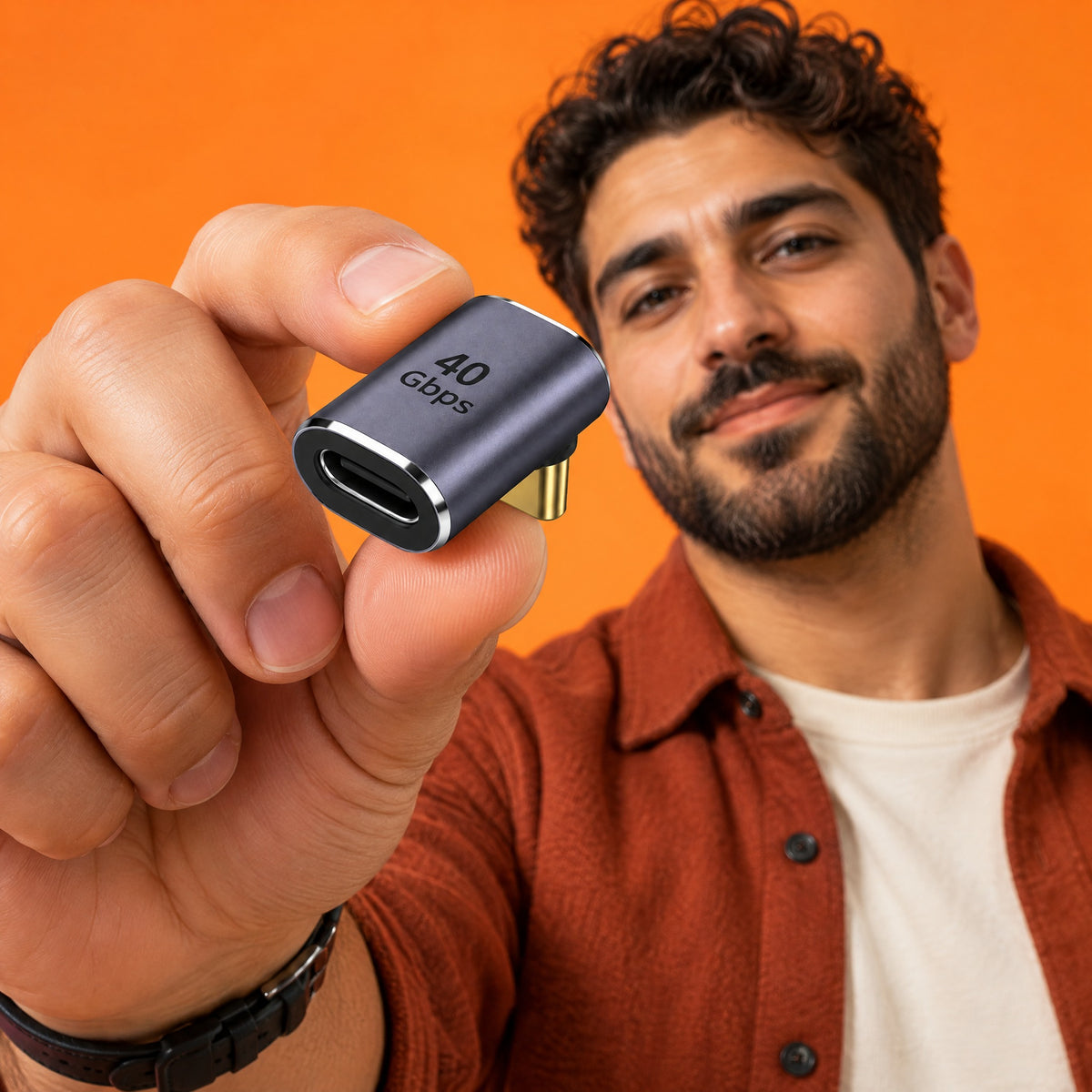 Man holding an Elbow Up USB-C adapter towards the camera, gold plug at a right angle under the grey aluminium body