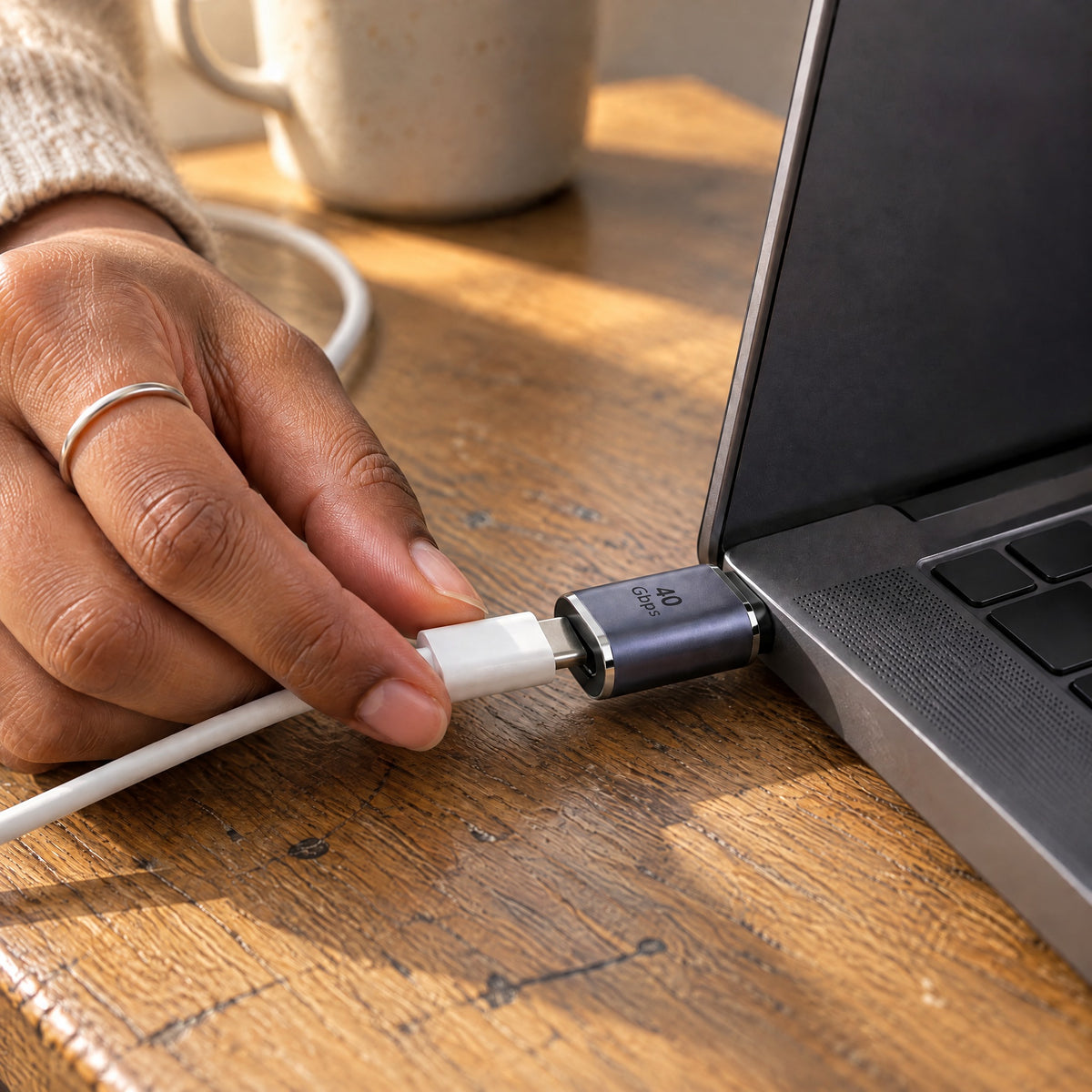 Hand plugging a white USB-C cable into a Straight USB-C extender fitted to the side of a laptop