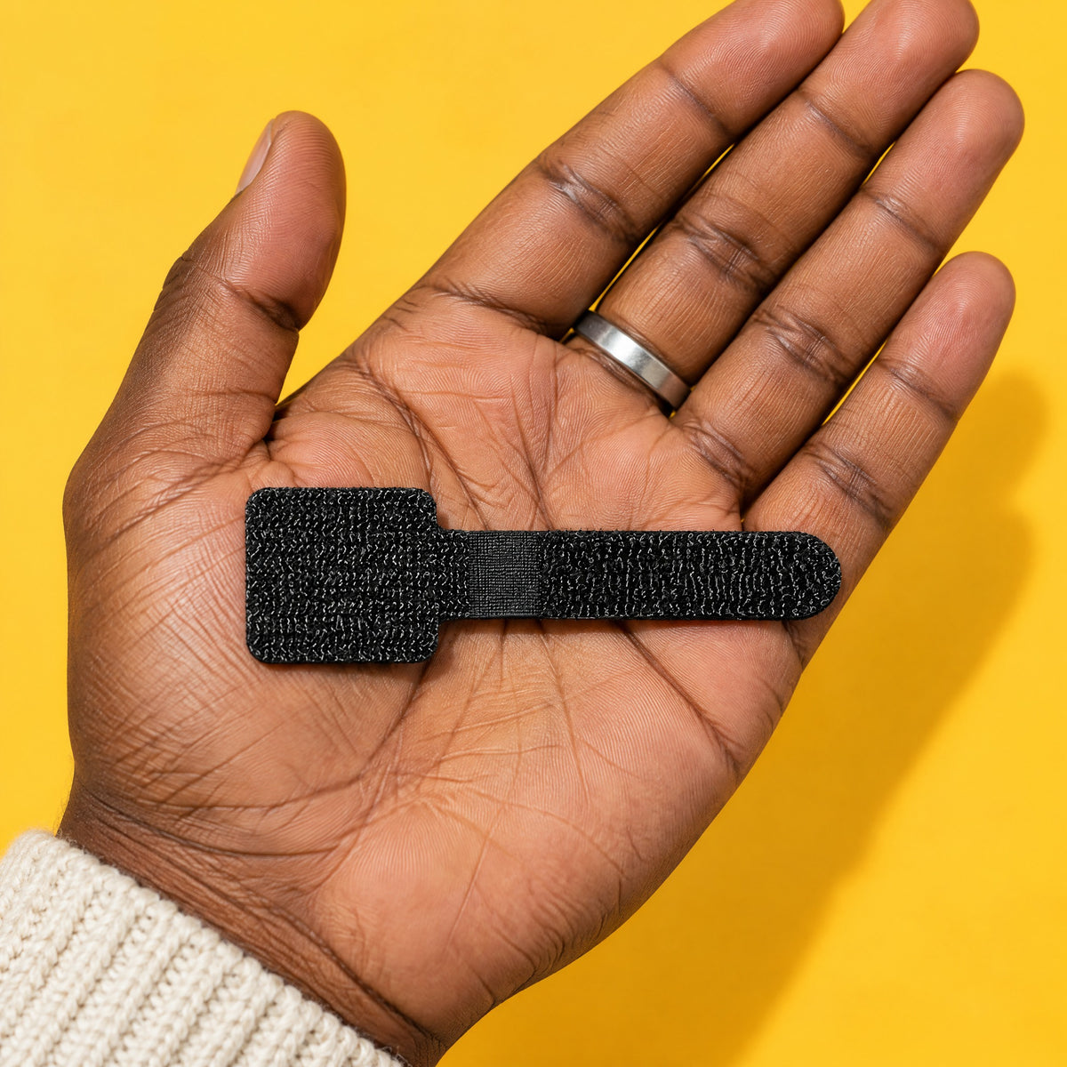 Black Velor cable tie lying flat on an open palm, about as long as the palm