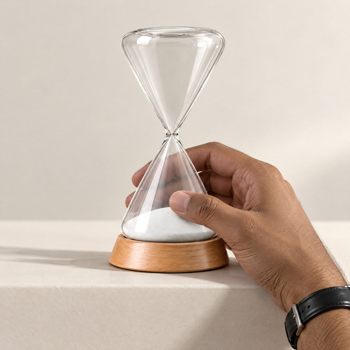 Hand reaching up to turn the Ebb hourglass over once the white sand has run through