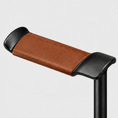 Close-up of the curved tan leather rest between two black aluminium end caps