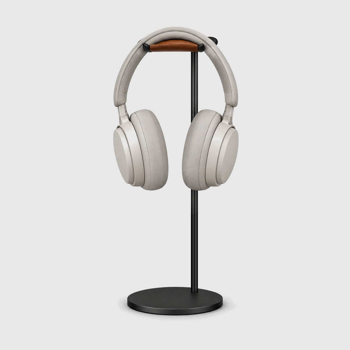 Front view of the black headphone stand with over-ear headphones resting on the leather rest