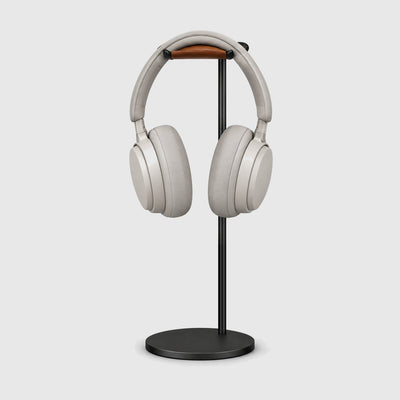 Front view of the black headphone stand with over-ear headphones resting on the leather rest