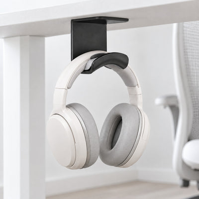 Black Eave under-desk headphone hook holding white headphones beneath a white desk