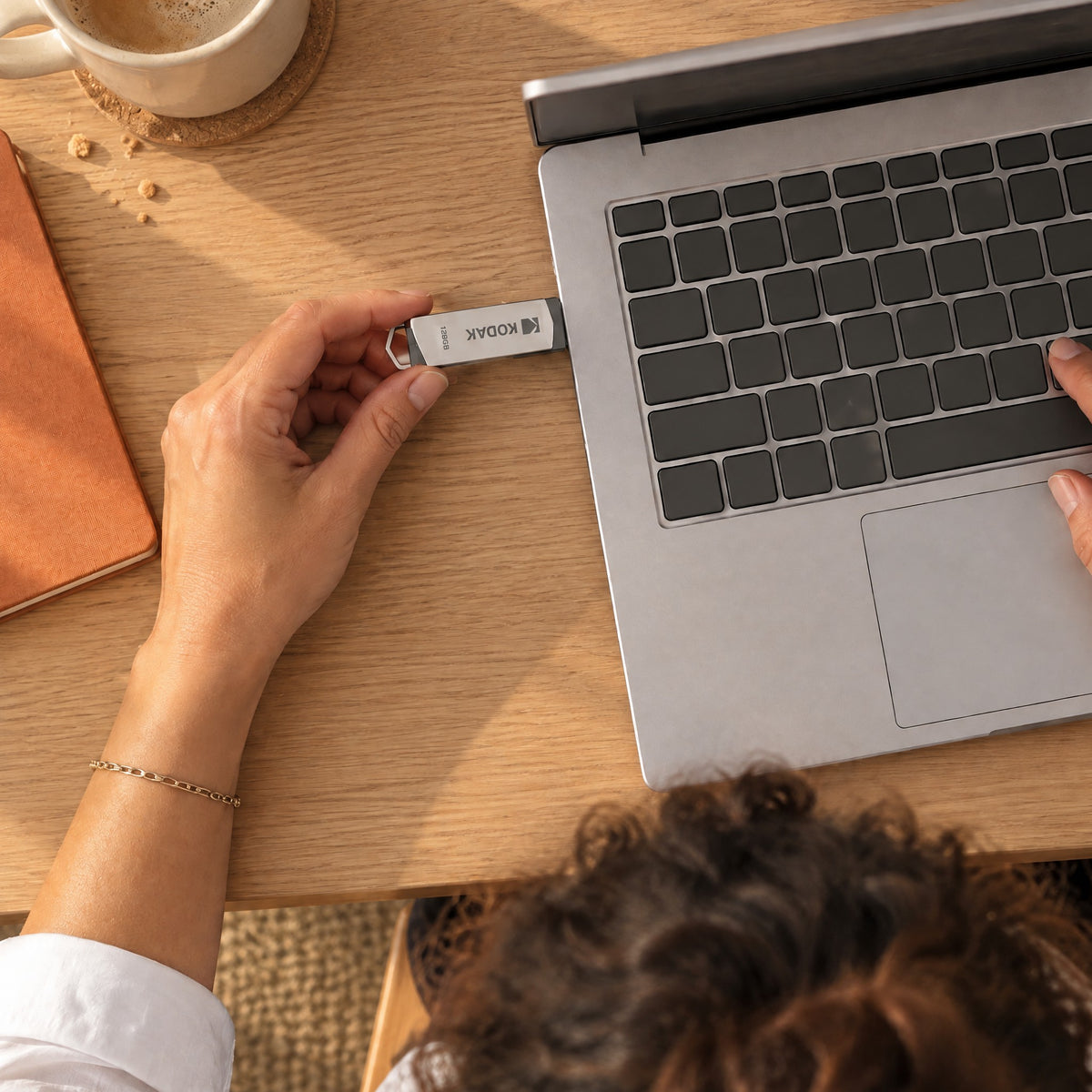 Woman plugging the Ferry flash drive into the side of her laptop, seen from above