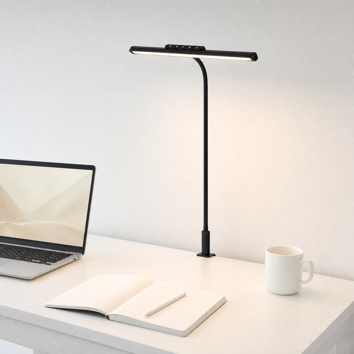 Black Heron clamp-on LED desk lamp lighting a white desk with a laptop and an open notebook