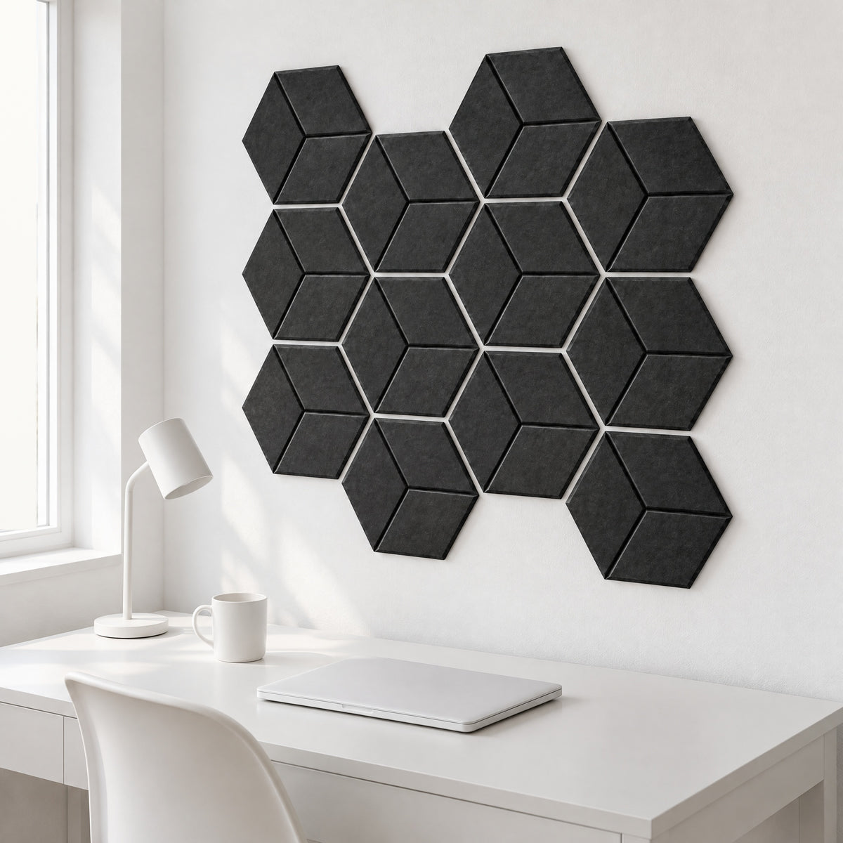 Twelve black Hive cube hexagon acoustic panels in a honeycomb on a white wall above a white desk
