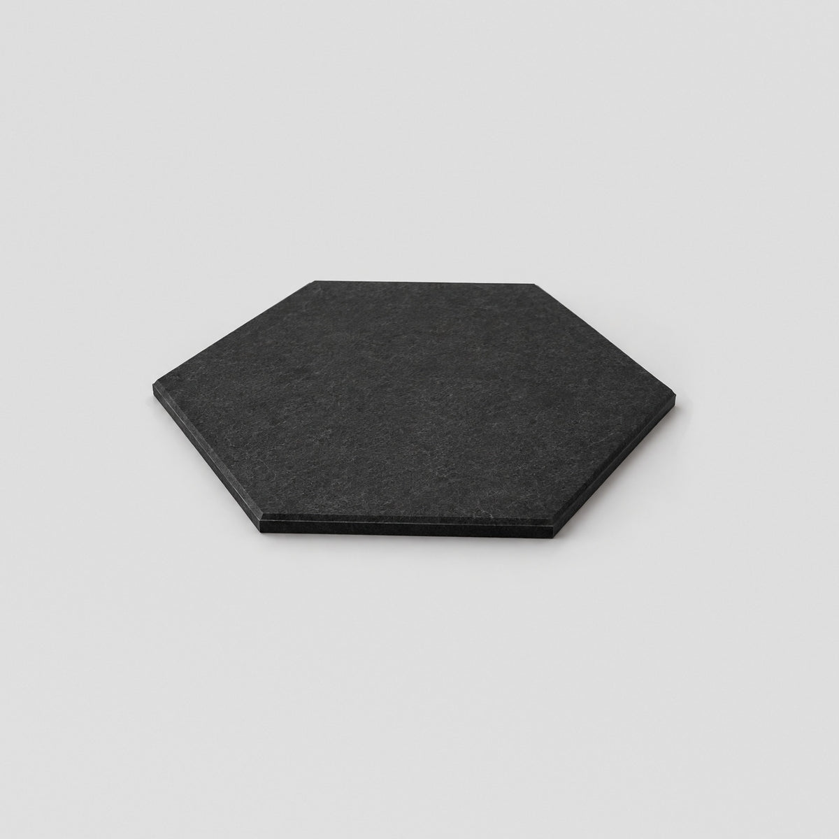 Black plain Hive hexagon felt acoustic panel, seen at an angle to show its thin edge
