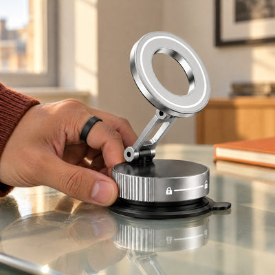 Hand turning the ribbed base of the silver Limpet mount to lock its suction disc onto a glass desk