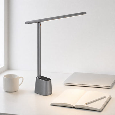 Grey Lintel folding LED desk lamp switched on over an open notebook on a white desk