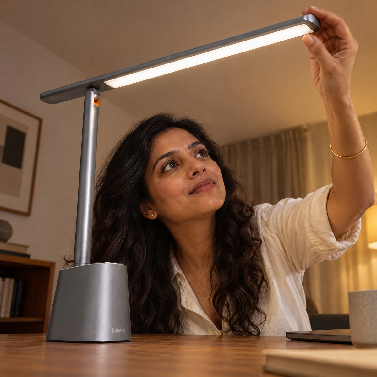 Woman adjusting the light bar of the grey Lintel desk lamp above her desk in the evening