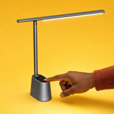 Fingertip tapping the touch button on the base of the grey Lintel desk lamp