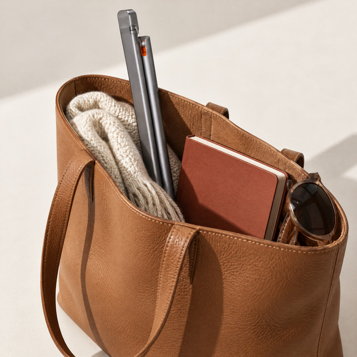 Grey Lintel desk lamp folded slim, standing in a tan leather tote bag