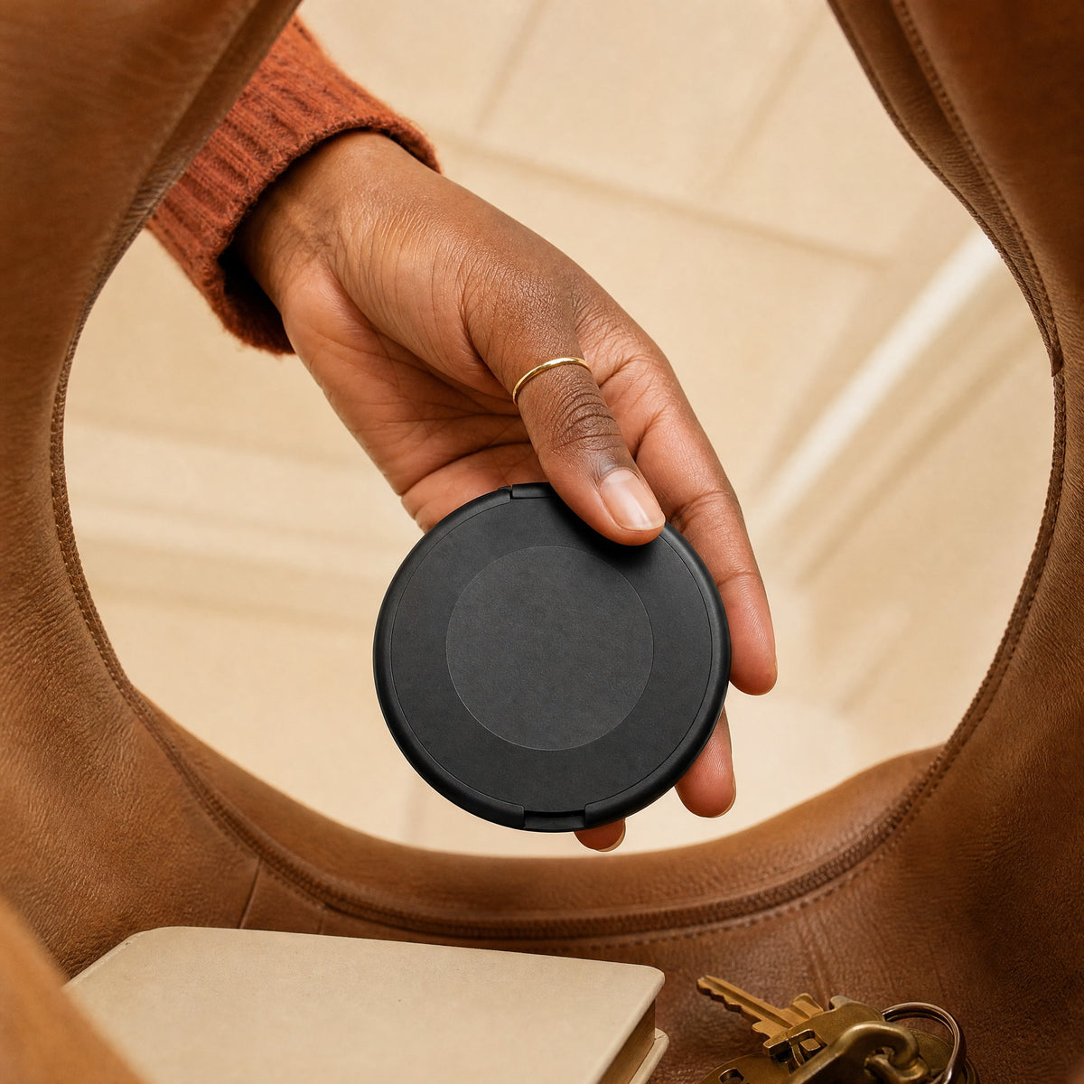 Hand lifting a closed Locket case out of a leather tote bag