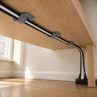 Three grey Velor cable ties holding black and white cables under an oak desk