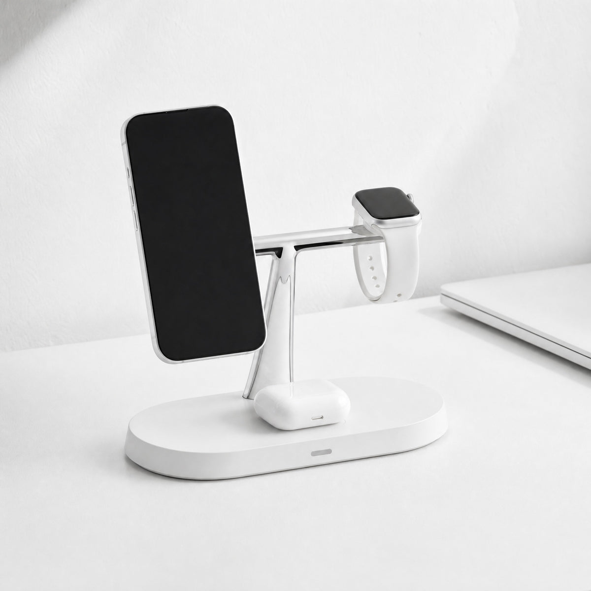 Trio 3-in-1 charging stand in white on a white desk, charging a phone, a watch and an earbuds case
