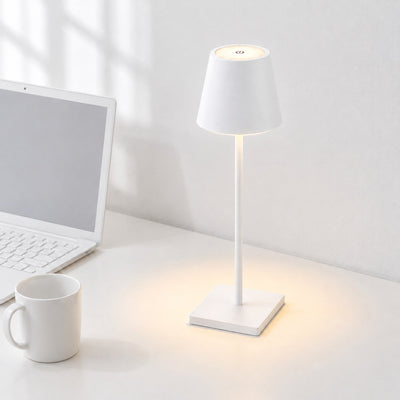 Vesper cordless LED table lamp in white, switched on, on a white desk beside a laptop and a white mug